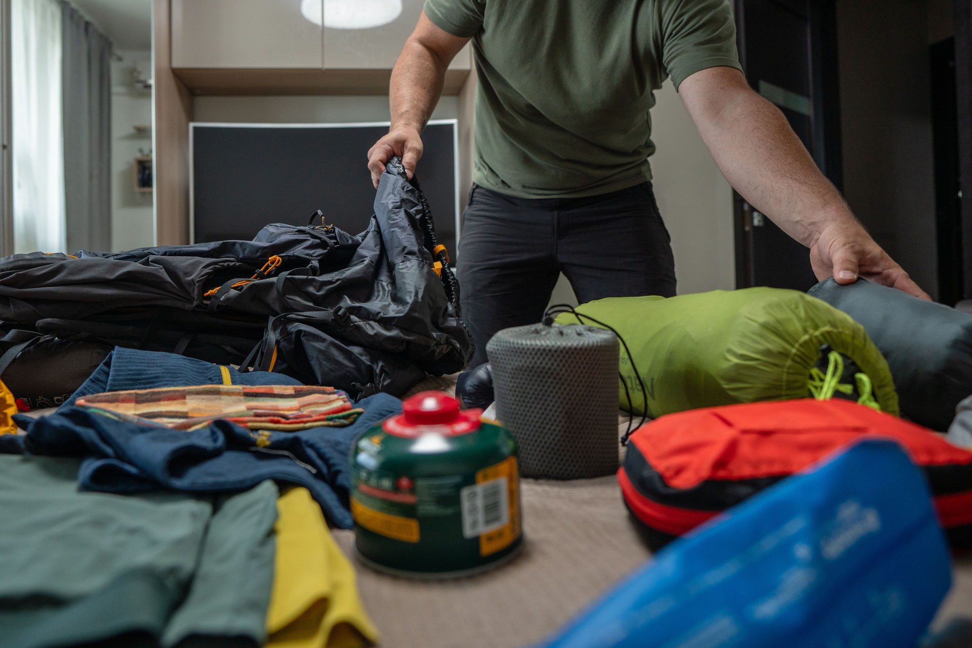 A man packing tourist equipment in a backpack, preparing for a hike